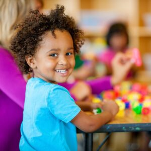 young boy playing at a table with other kids