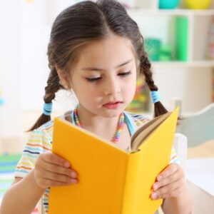 young girl reading a book with a yellow cover