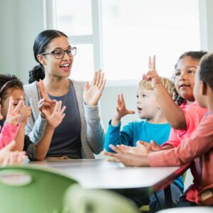 teacher working with a group of young kids at a table
