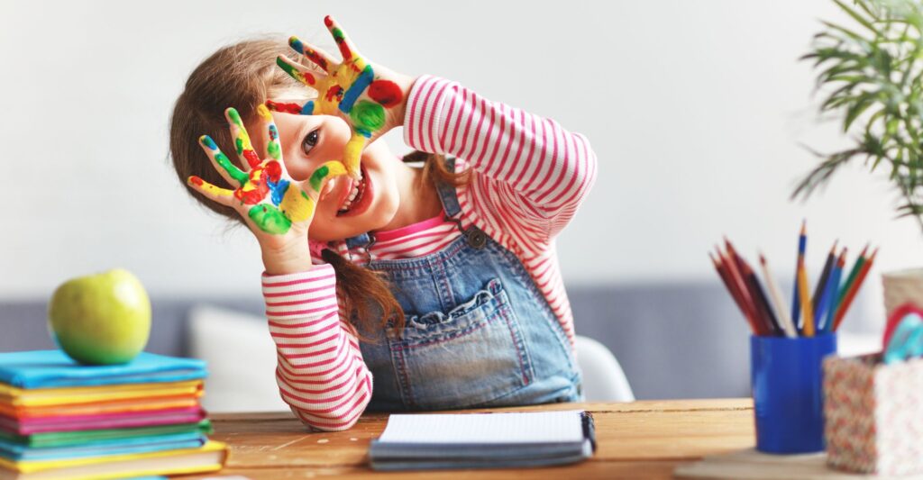 Preschool-aged child with paint on her hands.