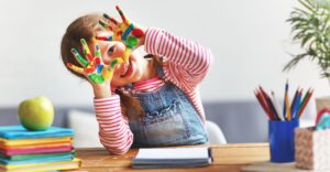 Preschool-aged child with paint on her hands.