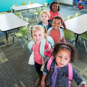 Young children with backpacks on looking happy. 