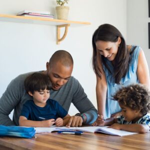 two parent helping their kids study at a table