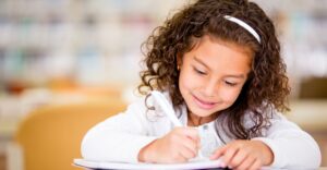 a girl smiling and writing