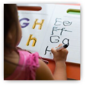 preschool girl writing alphabet