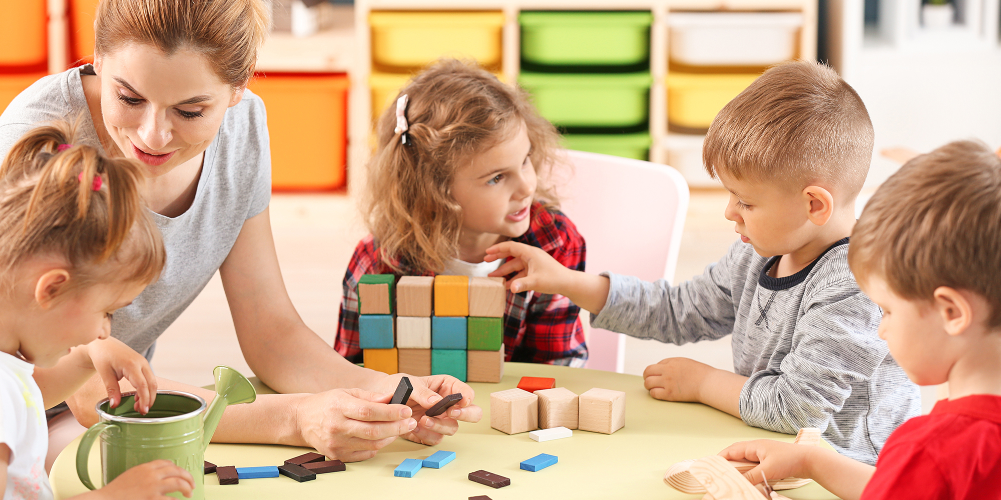 Nursery teacher with cute little children in kindergarten
