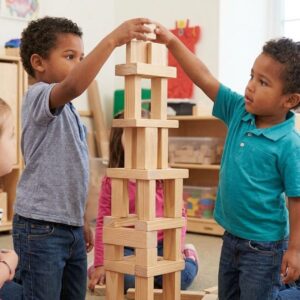 Young children building a complex tower with wooden blocks.